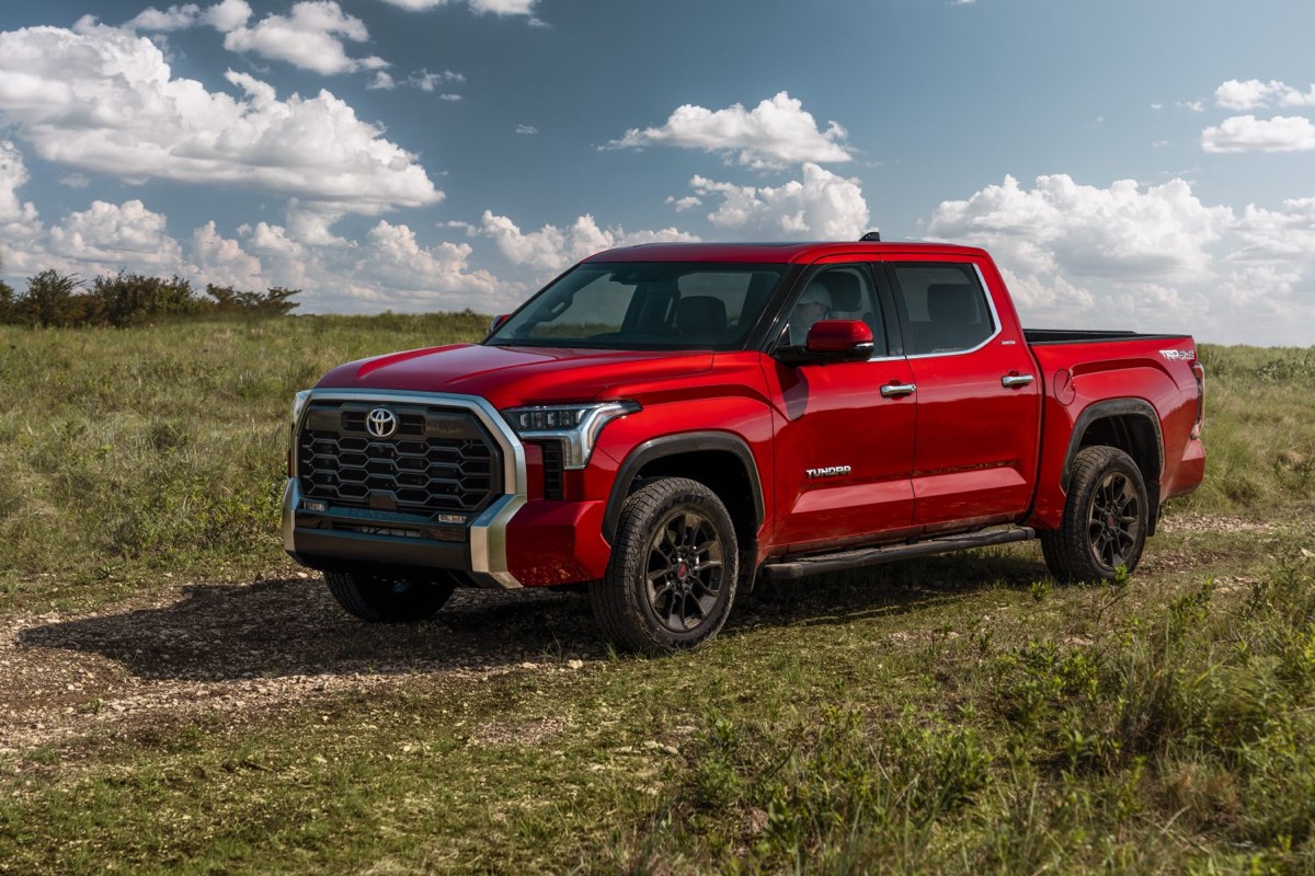 Vue 3/4 avant du Toyota Tundra Limited 2022 couleur rouge garé dans un champs d'herbes