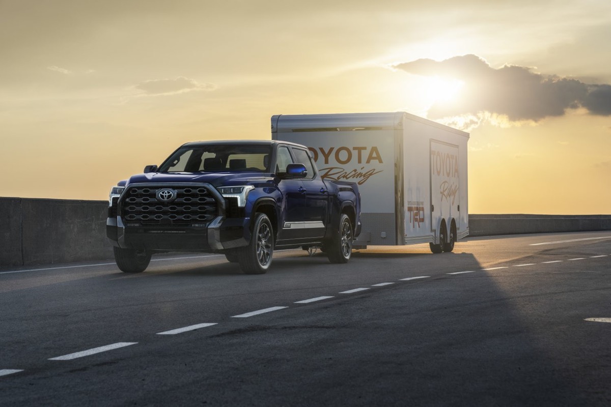 Vue 3/4 avant du Toyota Tundra Platinum 2022 remorquant la caisse TOYOTA Racing sur la route