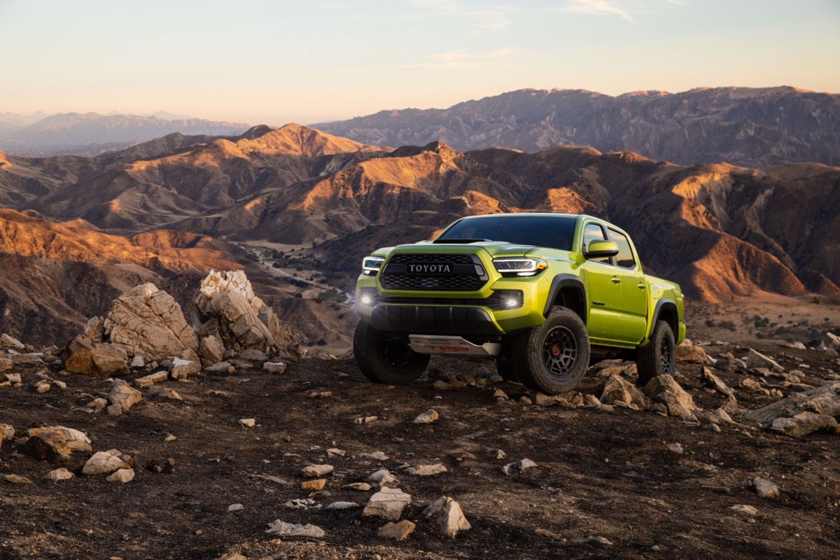 Le Toyota Tacoma TRD Pro 2022 de couleur Lime électrique avec ses phares de route automatiques allumés et garé sur une montagne