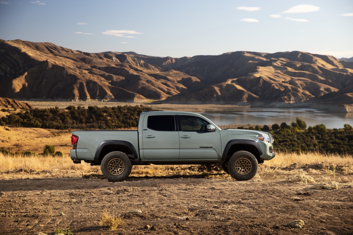 Vue latérale du Toyota Tacoma édition Trail 2022 de couleur Roche Lunaire garé non loin des montagnes