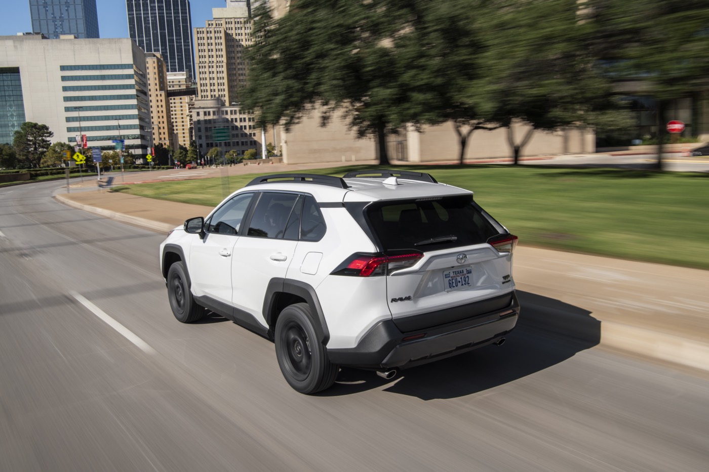 Vue 3/4 arrière d'un VUS Toyota RAV4 TRD Hors route 2022 blanc roulant sur un boulevard en ville