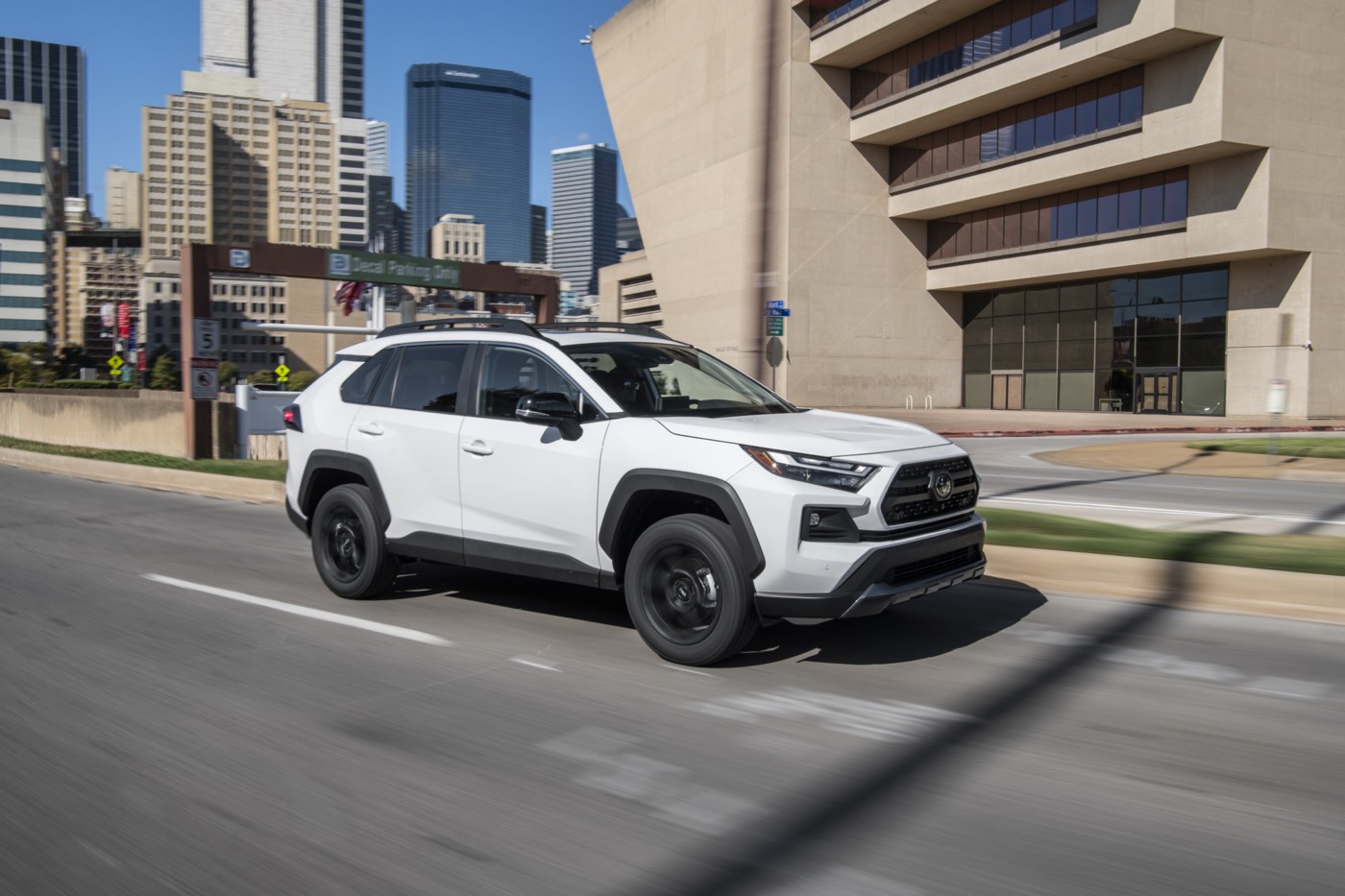 Vue 3/4 avant d'un VUS Toyota RAV4 TRD Hors route 2022 blanc roulant sur un boulevard en ville