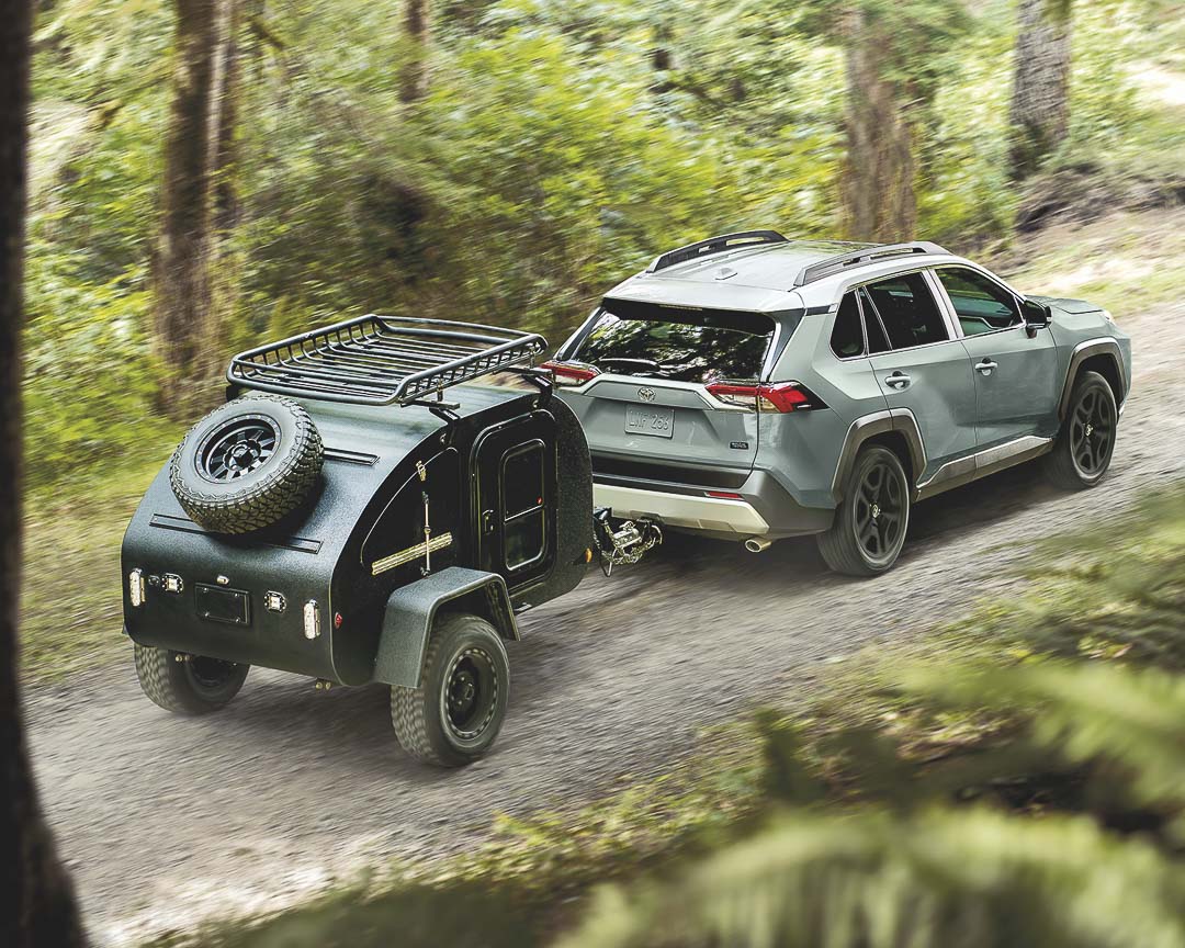 vue latérale arrière du Toyota RAV4 2022 remorquant une tente roulotte sur un sentier de terre