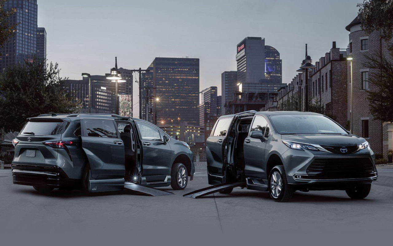 vue de deux Toyota Sienna 2023, la portière ouverte avec une rampe d'accès sur une place publique en ville, en soirée