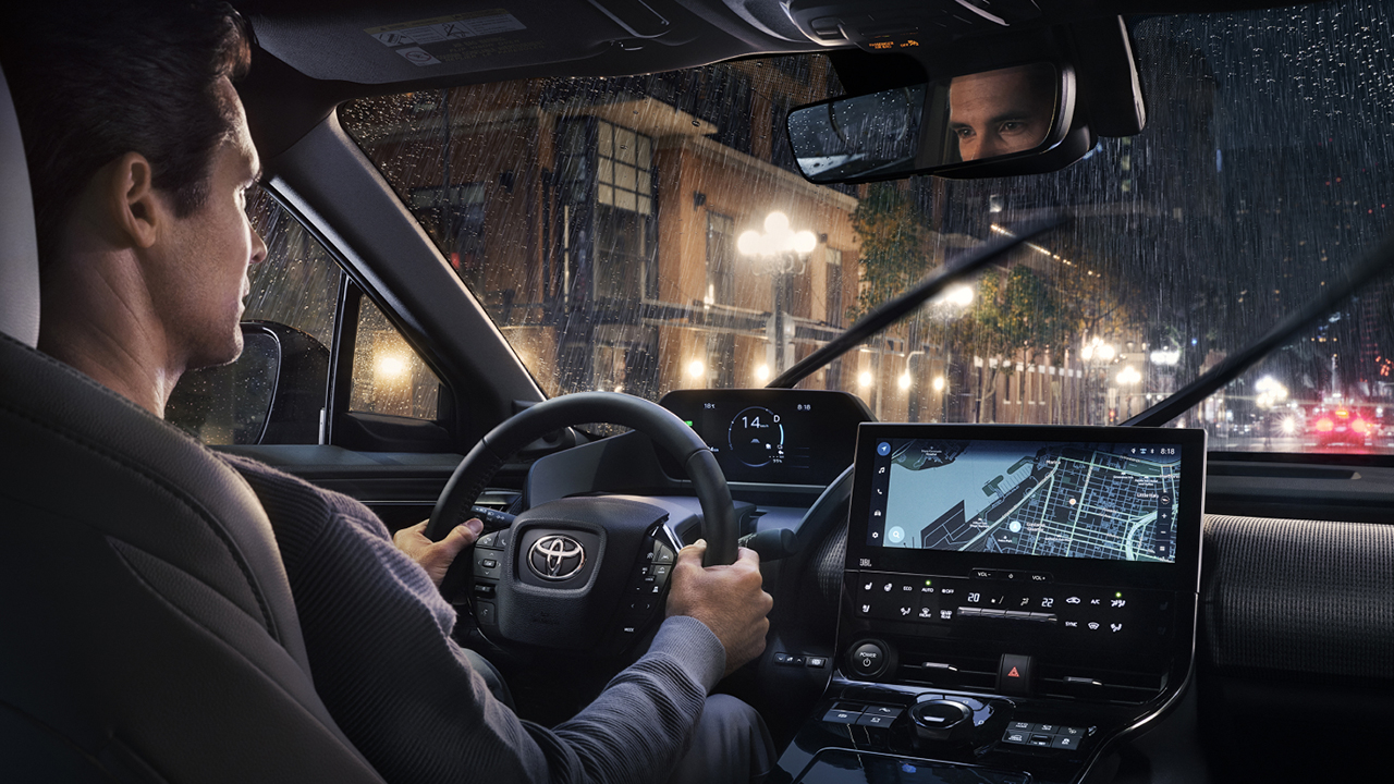 Vue intérieur du Toyota BZ4x 2024 sur route en ville, un soir de pluie