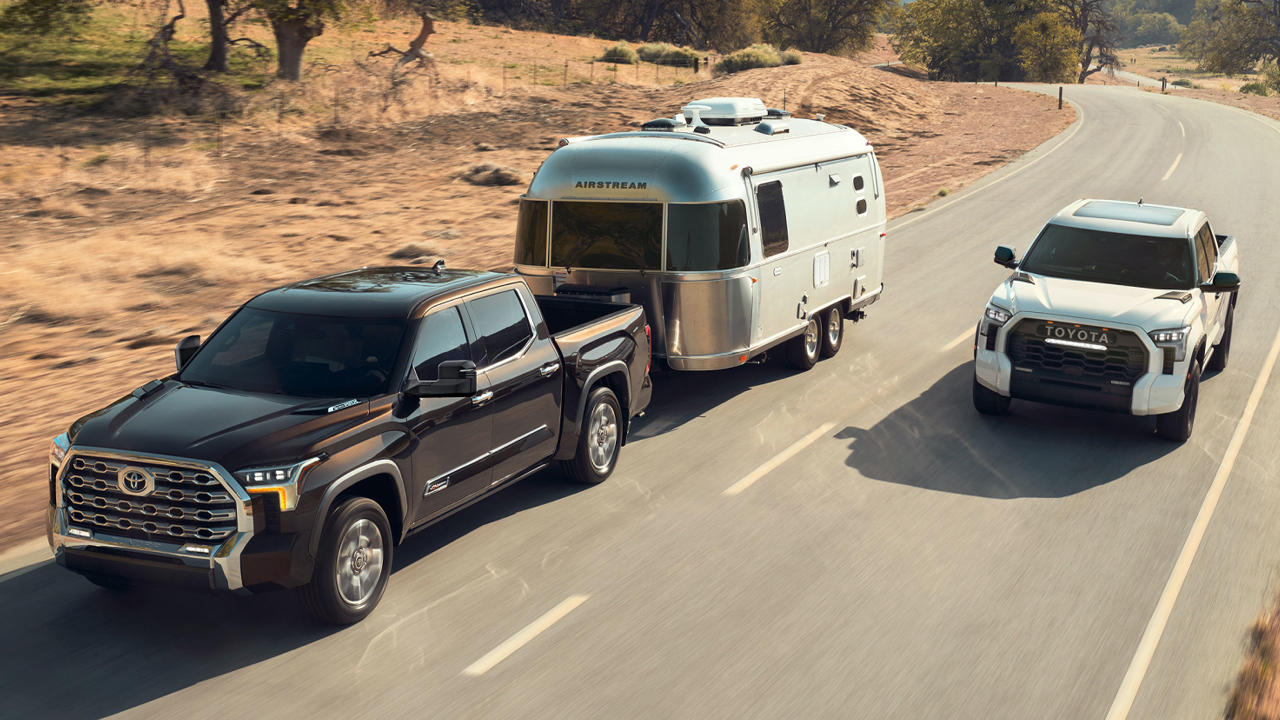 Vue avant et latérale d'un duo de Toyota Tundra 2024 sur route, un avec remorque et l'autre en pleine puissance en dépassement