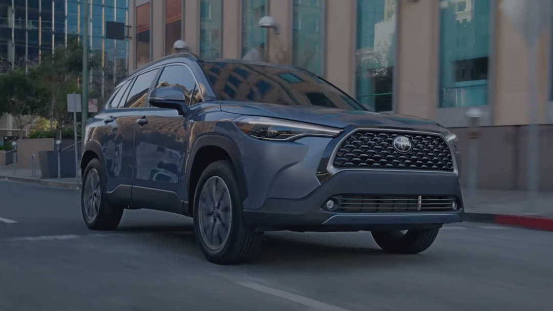 Le Toyota corolla cross roulant en ville lumières allumées.
