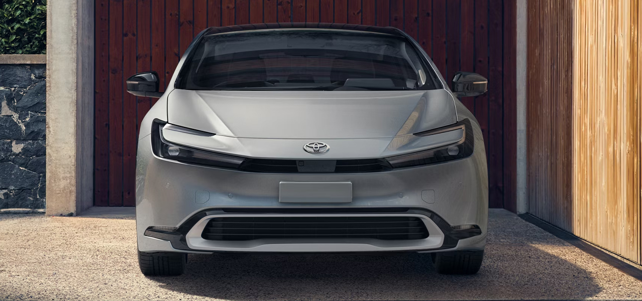 Vue avant de la Toyota Prius 2024 garé devant une maison et une porte de garage en bois
